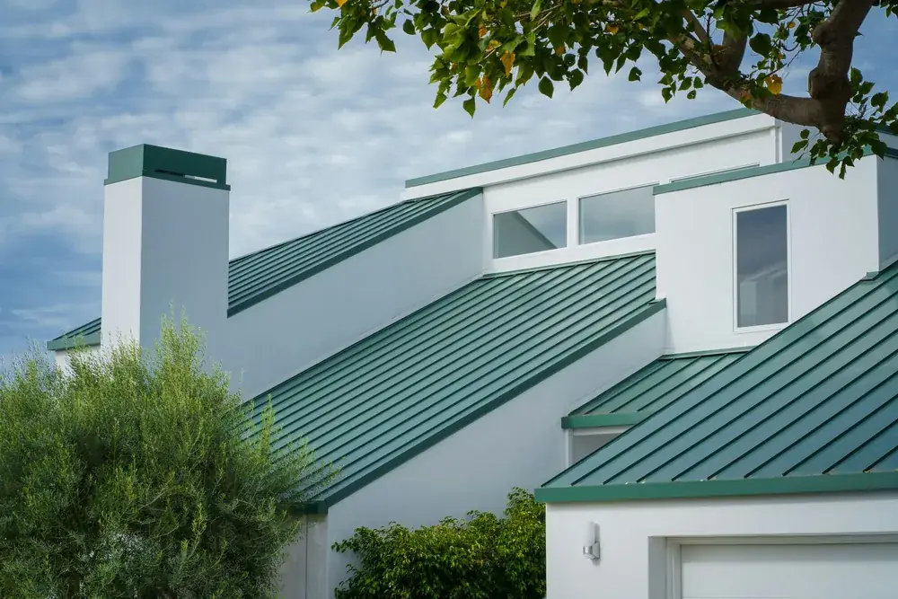 Home with a green standing-seam metal roof among coastal trees